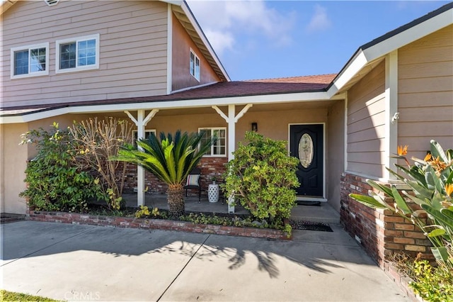 doorway to property with brick siding and a porch