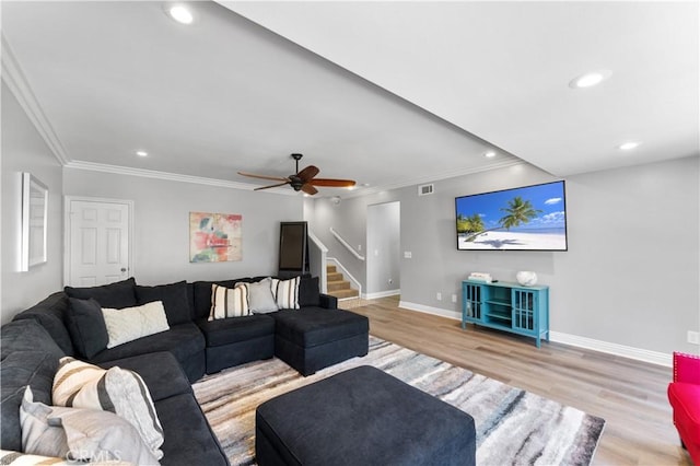 living area with light wood-type flooring, baseboards, stairway, and ornamental molding