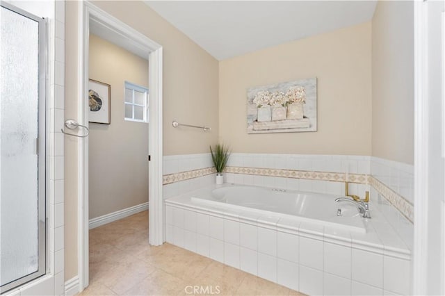 bathroom with tile patterned flooring, a garden tub, a shower stall, and baseboards