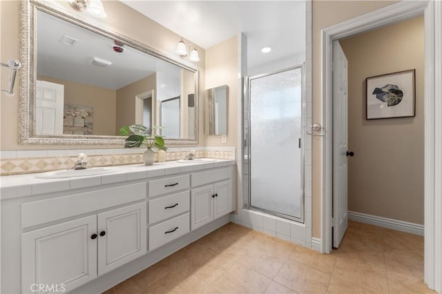 full bathroom featuring double vanity, a stall shower, and a sink