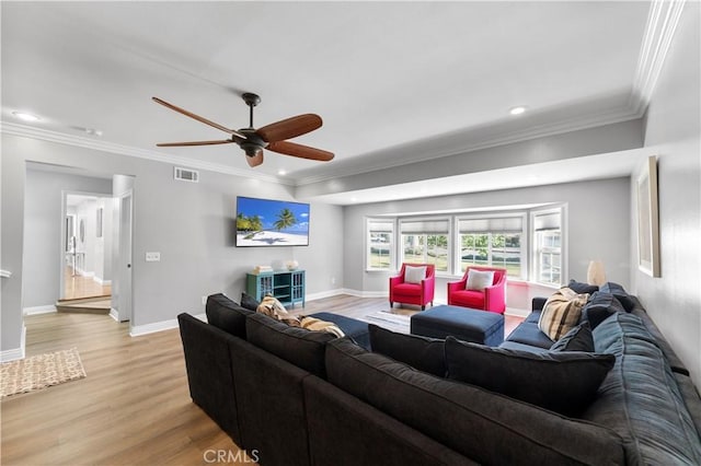 living area with crown molding, baseboards, visible vents, and light wood-style floors