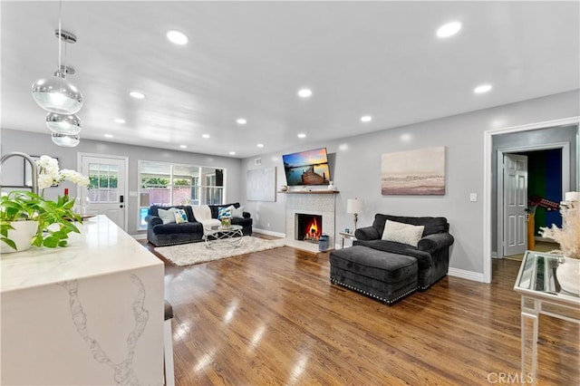 living area with a fireplace with flush hearth, recessed lighting, and wood finished floors