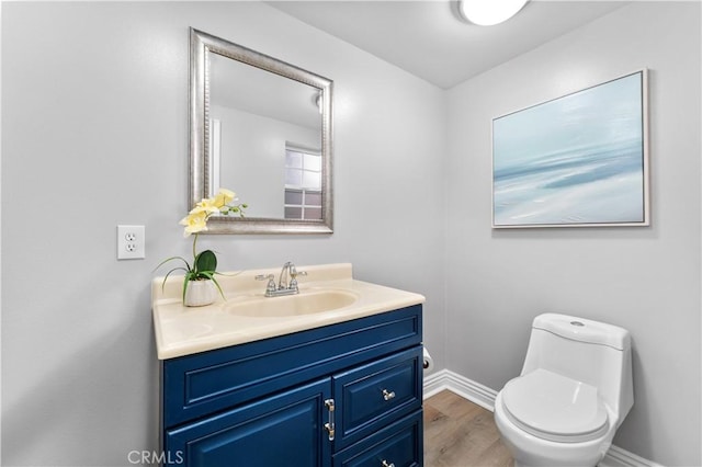 half bathroom featuring toilet, wood finished floors, vanity, and baseboards