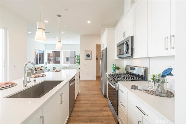 kitchen with sink, hanging light fixtures, white cabinets, and stainless steel appliances