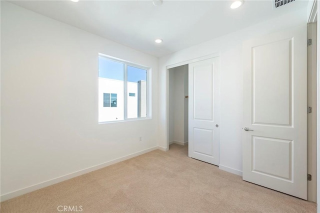 unfurnished bedroom featuring a closet and light colored carpet