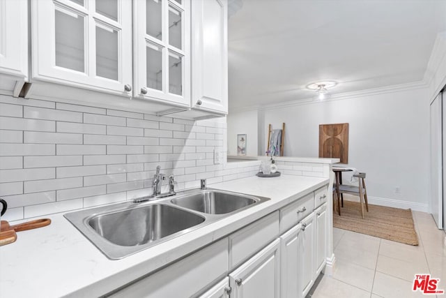 kitchen featuring light tile patterned floors, white cabinetry, backsplash, crown molding, and sink