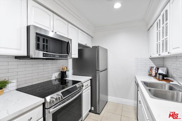 kitchen with light tile patterned floors, stainless steel appliances, ornamental molding, white cabinets, and sink