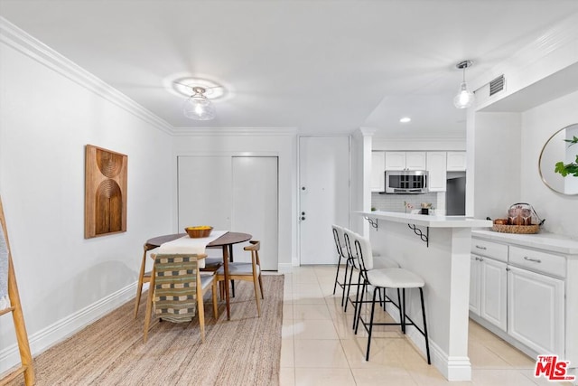 dining area with light tile patterned flooring and ornamental molding