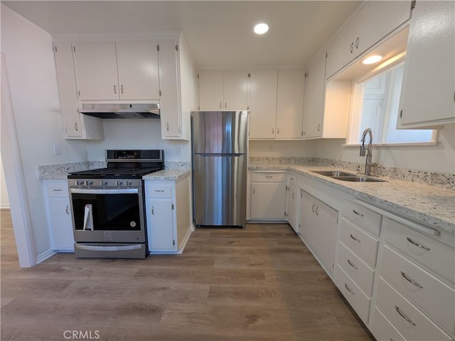 kitchen featuring appliances with stainless steel finishes, white cabinetry, a sink, light wood-type flooring, and under cabinet range hood