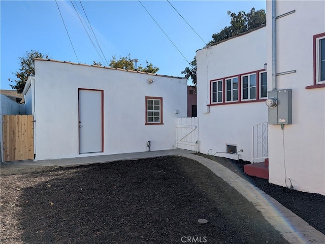 exterior space featuring a gate, fence, and stucco siding