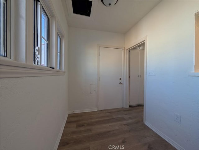 corridor with dark wood-style flooring and baseboards