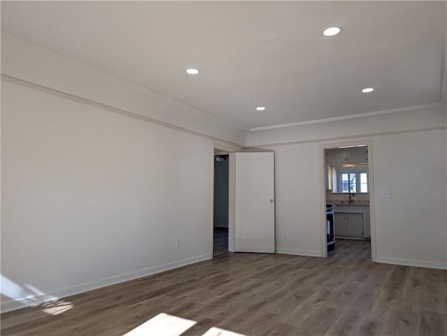 empty room with ornamental molding, dark wood-type flooring, recessed lighting, and baseboards