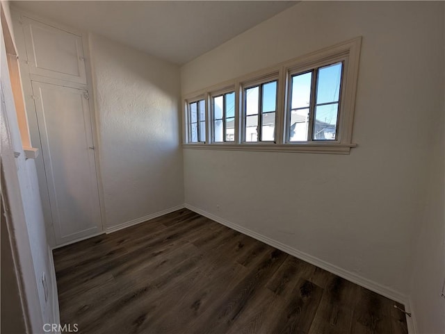 unfurnished room with baseboards and dark wood-style flooring