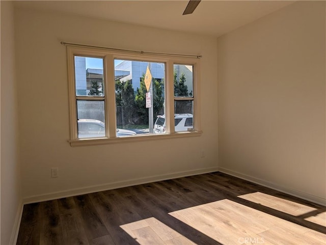 empty room featuring ceiling fan, dark wood-style flooring, and baseboards