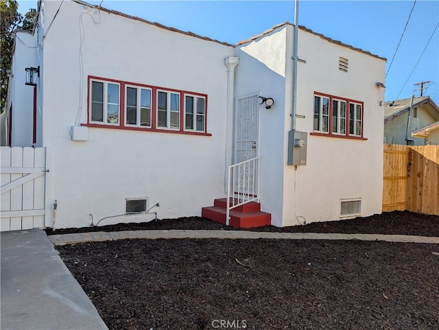 view of side of property with entry steps, fence, and stucco siding