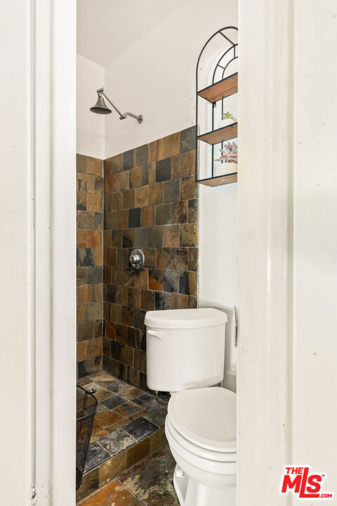 bathroom featuring toilet and tiled shower