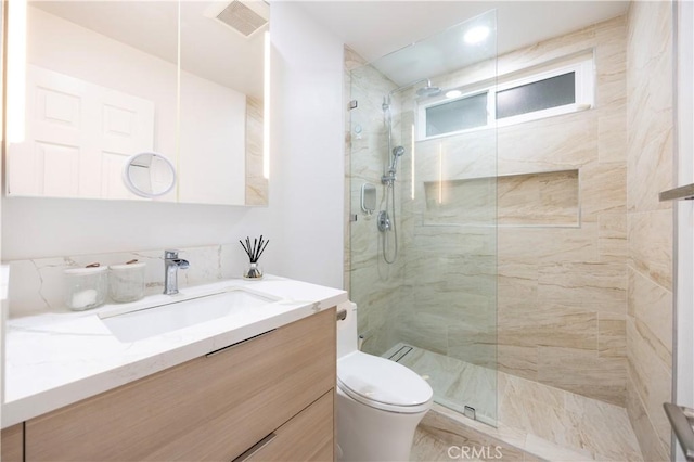 bathroom featuring vanity, toilet, and a tile shower