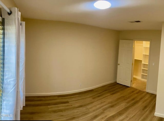 unfurnished bedroom with a spacious closet, hardwood / wood-style floors, and a closet