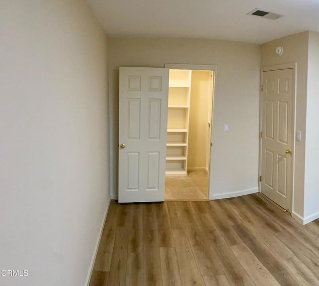 unfurnished bedroom with a spacious closet, a closet, and light wood-type flooring