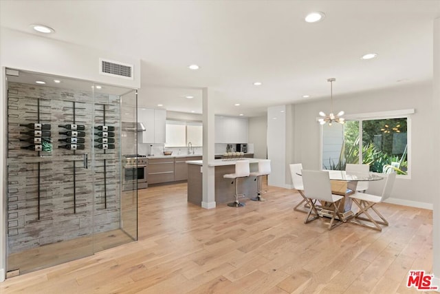 dining area with sink, light wood-type flooring, and an inviting chandelier