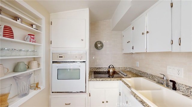 kitchen with sink, oven, white cabinetry, and black electric cooktop