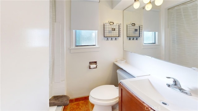 bathroom with toilet, tile patterned floors, a wealth of natural light, and vanity