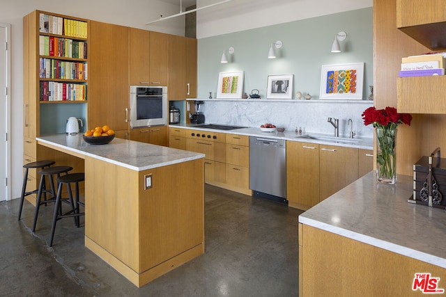 kitchen featuring kitchen peninsula, a breakfast bar, backsplash, appliances with stainless steel finishes, and sink