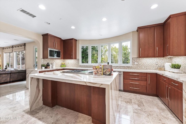 kitchen featuring a wealth of natural light, light stone counters, and built in microwave