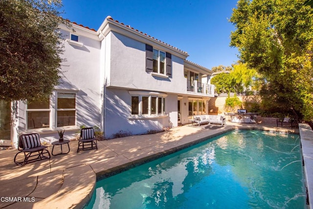 rear view of house with an outdoor hangout area, a balcony, a patio, and pool water feature