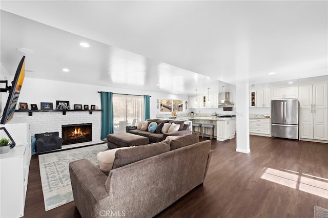 living room featuring dark wood-type flooring and a brick fireplace