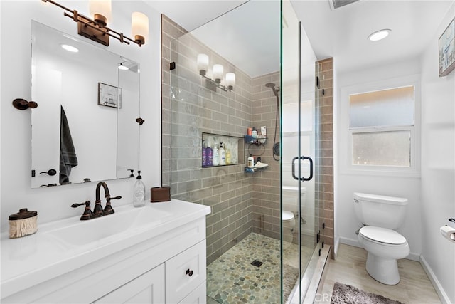 full bath featuring toilet, wood finished floors, vanity, a shower stall, and baseboards