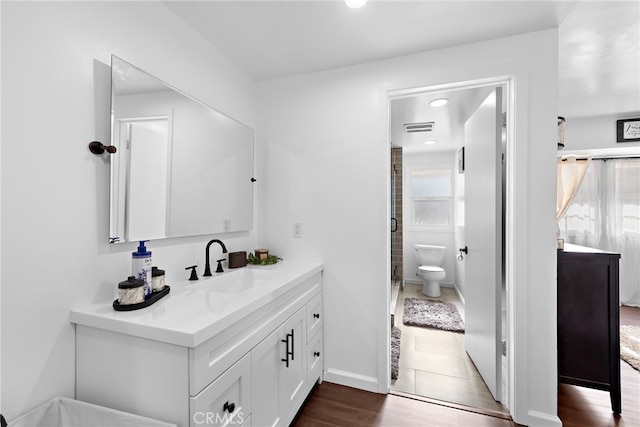 full bath featuring a stall shower, toilet, visible vents, vanity, and wood finished floors