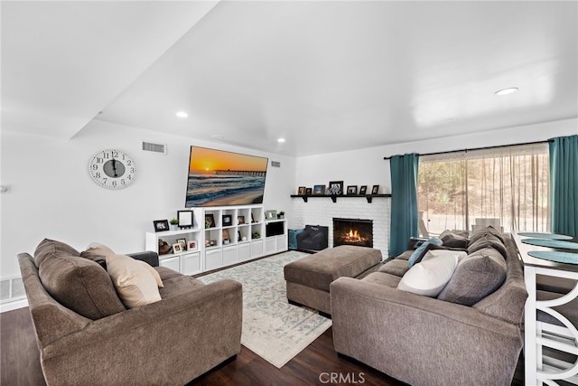 living area featuring recessed lighting, visible vents, a brick fireplace, and dark wood-style floors