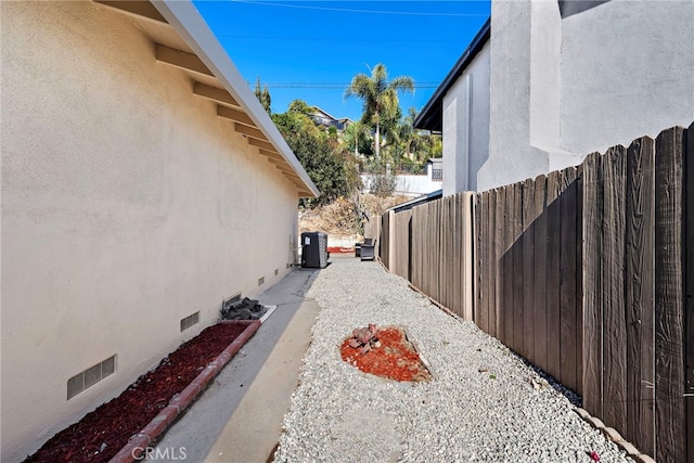 view of home's exterior with central air condition unit, fence, stucco siding, and crawl space