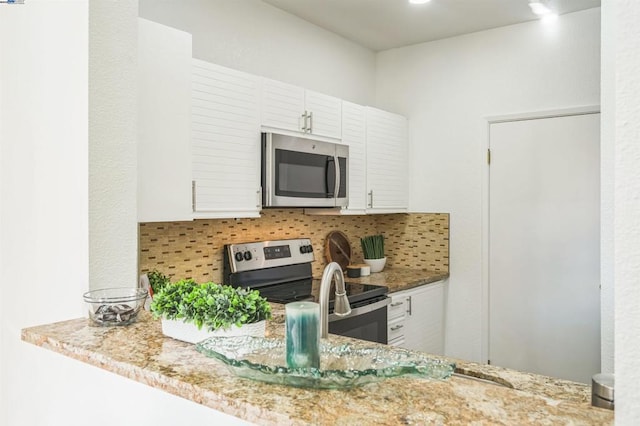 kitchen with appliances with stainless steel finishes, white cabinetry, and backsplash