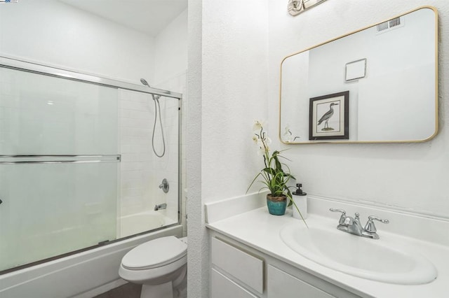 full bathroom featuring bath / shower combo with glass door, vanity, and toilet