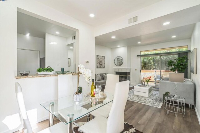 dining area with dark hardwood / wood-style flooring and a tiled fireplace