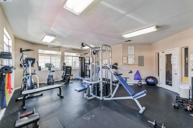 gym with electric panel and a textured ceiling