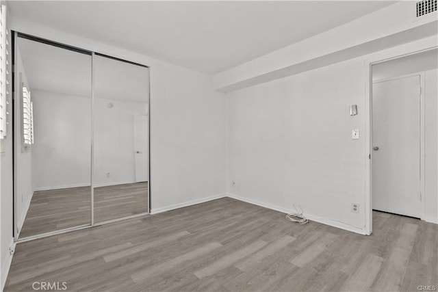 unfurnished bedroom with a closet and light hardwood / wood-style flooring