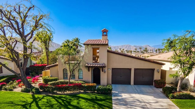 mediterranean / spanish house with a garage, a mountain view, and a front lawn