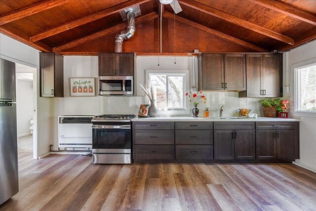 kitchen with sink, stainless steel appliances, vaulted ceiling with beams, and wooden ceiling