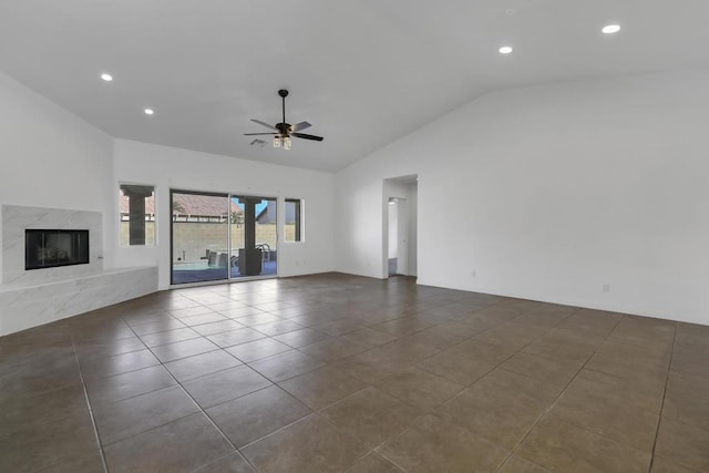 unfurnished living room featuring lofted ceiling, dark tile patterned flooring, a fireplace, and ceiling fan