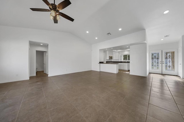 unfurnished living room with vaulted ceiling, dark tile patterned flooring, ceiling fan, and french doors