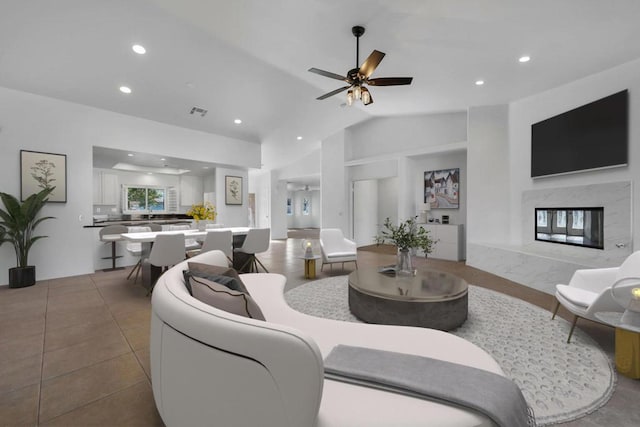 living room featuring vaulted ceiling, light tile patterned flooring, ceiling fan, and a fireplace