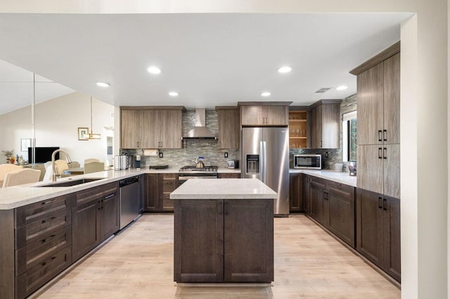 kitchen with kitchen peninsula, wall chimney exhaust hood, a center island, stainless steel appliances, and sink