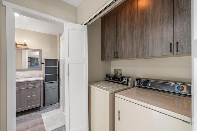 laundry room featuring cabinets, light hardwood / wood-style flooring, and washer and clothes dryer