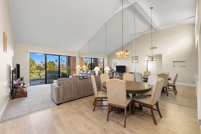 dining room with high vaulted ceiling, a chandelier, and light wood-type flooring