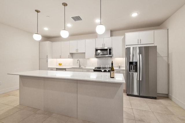 kitchen featuring decorative light fixtures, sink, white cabinetry, and stainless steel appliances