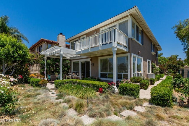 rear view of property featuring a balcony and a pergola