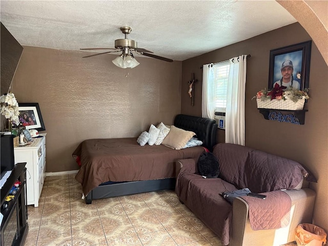 tiled bedroom featuring ceiling fan and a textured ceiling